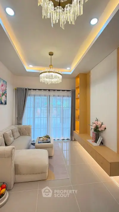 Elegant living room with modern chandelier and cozy sofa, featuring floor-to-ceiling windows and stylish decor.