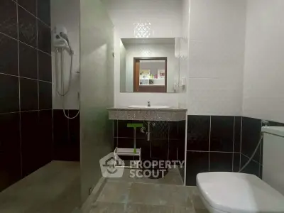 Modern bathroom with sleek black and white tiles, featuring a shower and stylish vanity.