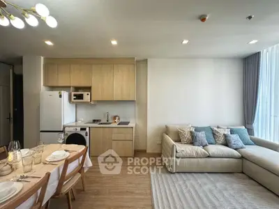 Modern open-plan living room with kitchen and dining area, featuring stylish furniture and natural light.
