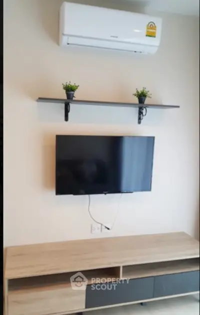 Modern living room with wall-mounted TV and air conditioner, sleek wooden console, and decorative shelf.
