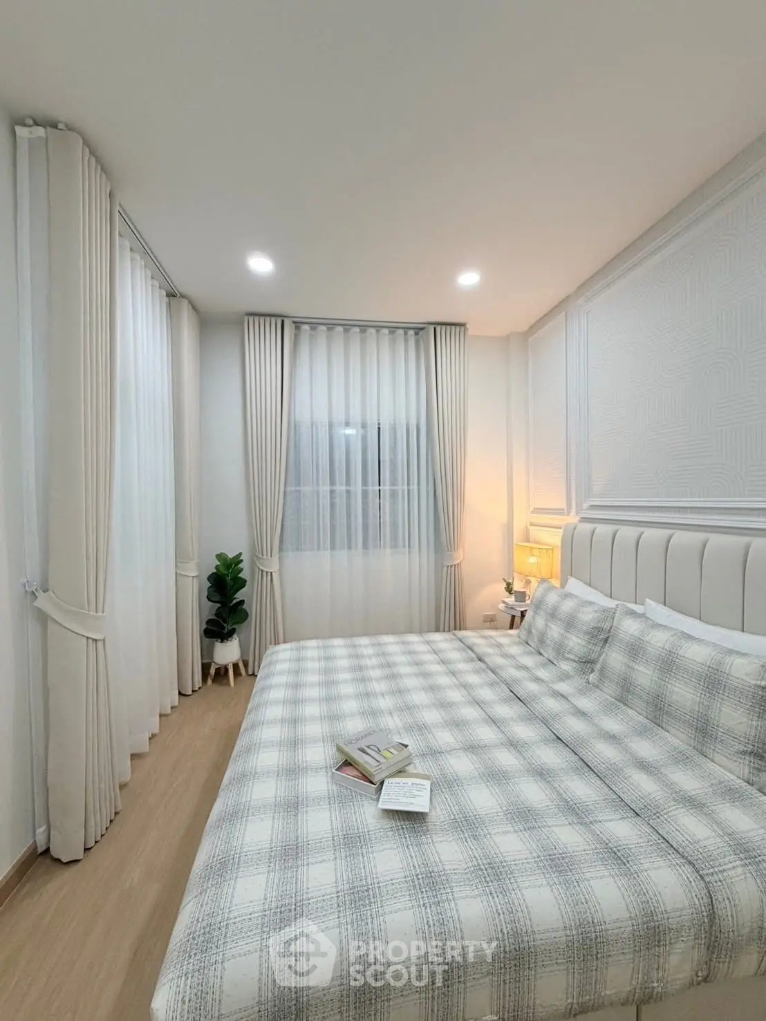 Elegant bedroom with cozy plaid bedding and soft lighting, perfect for relaxation.