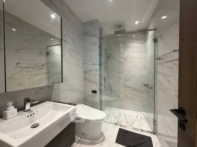 Luxurious modern bathroom with marble tiles and glass shower enclosure