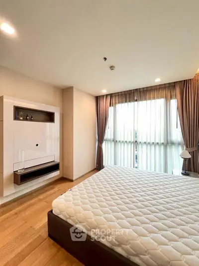 Spacious bedroom with large window and modern decor in a stylish apartment.