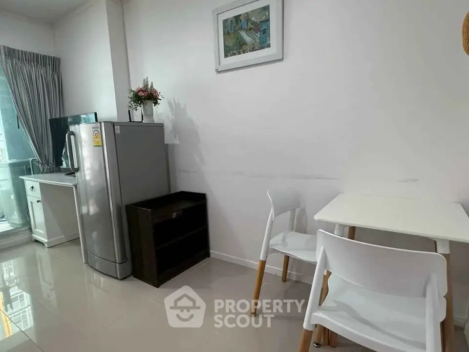 Modern kitchen with sleek appliances and dining area in a bright, minimalist apartment.