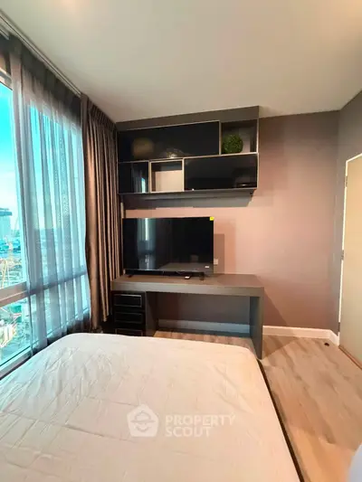 Modern bedroom with large window and sleek TV setup in urban apartment