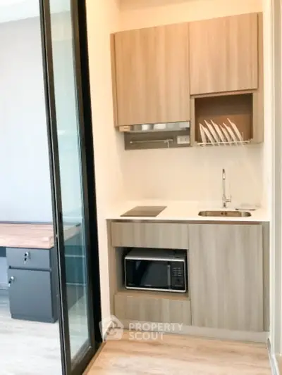 Modern compact kitchen with sleek wooden cabinets and built-in microwave