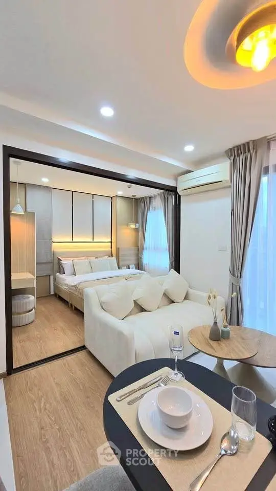 Modern open-plan living room with cozy bedroom, stylish decor, and elegant dining area in a contemporary apartment.