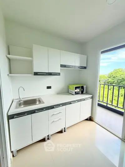 Modern kitchen with sleek cabinets and balcony view, perfect for culinary enthusiasts.