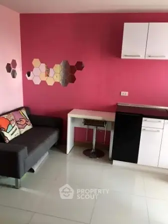 Modern compact living room with vibrant pink accent wall and sleek furniture