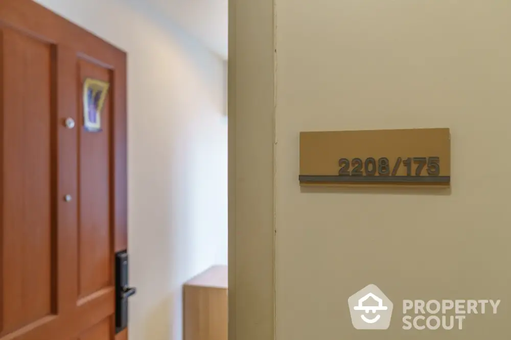 Modern apartment entrance with stylish door and unit number plaque.