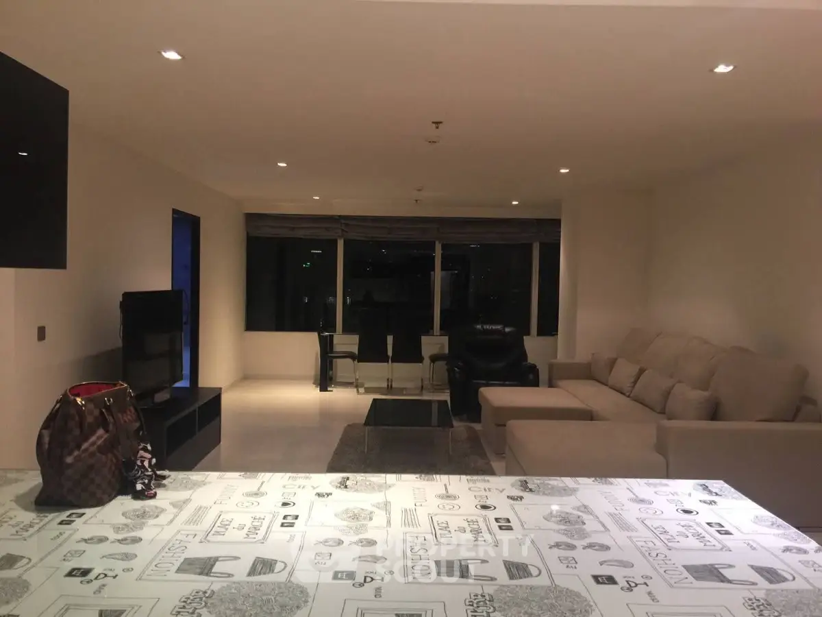 Spacious modern living room with stylish decor and large windows offering city views.