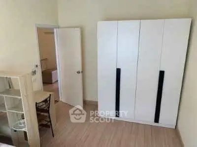 Spacious bedroom with modern wardrobe and open door leading to adjacent room.