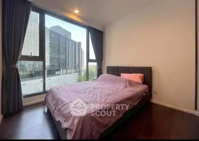 Modern bedroom with large window offering city view, featuring elegant curtains and stylish bed.