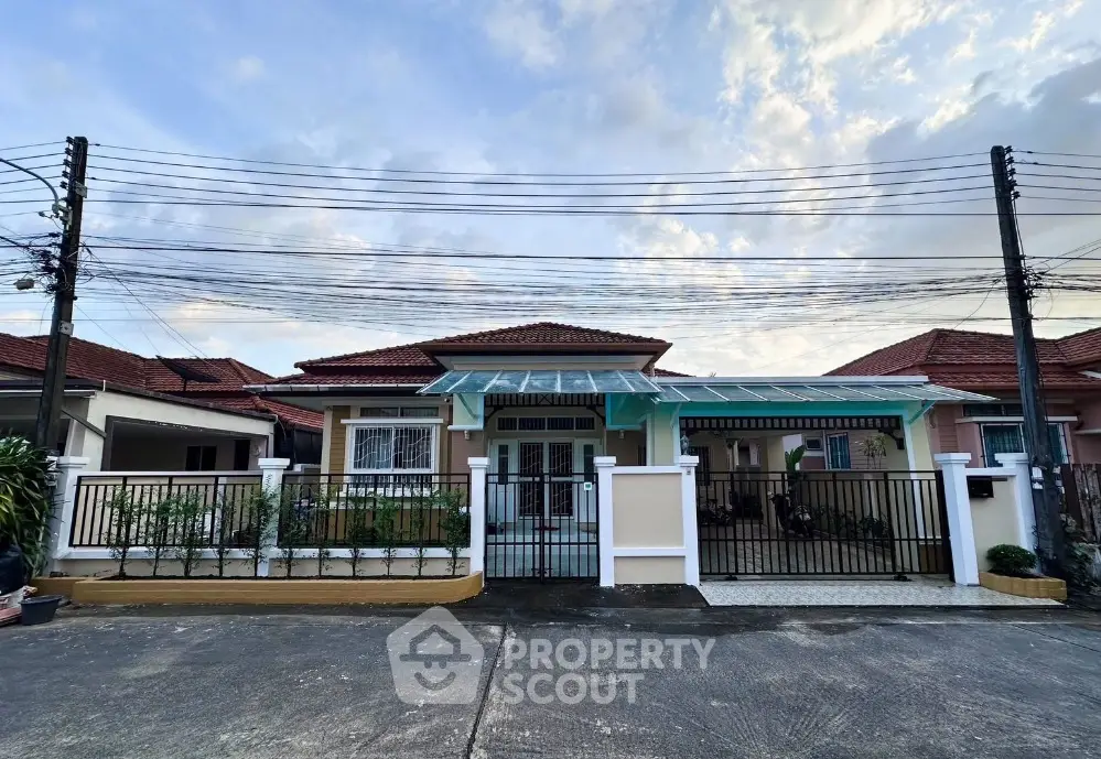 Charming single-story house with red roof and gated front yard in a serene neighborhood.