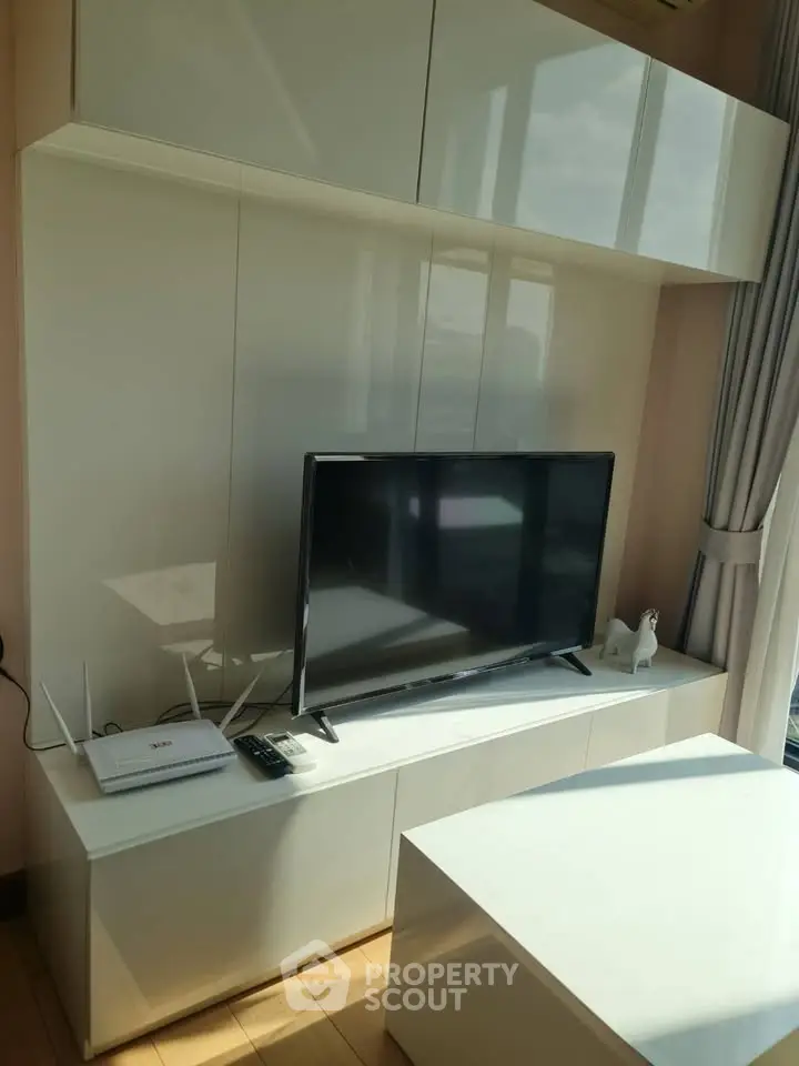 Modern living room with sleek TV setup and glossy white cabinets.