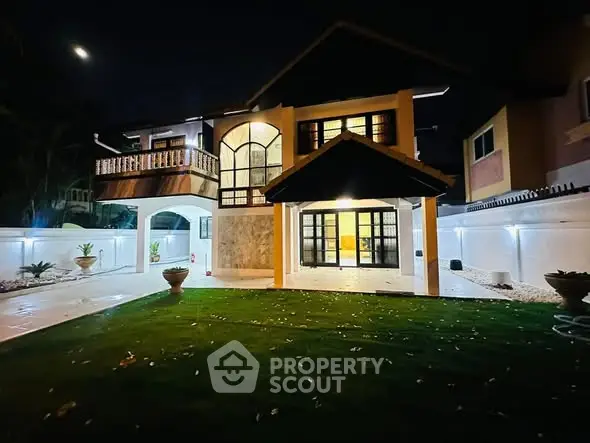 Stunning night view of a luxurious two-story house with elegant lighting and lush green lawn.