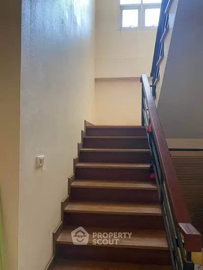 Spacious stairway with wooden steps and natural light from window, ideal for modern homes.