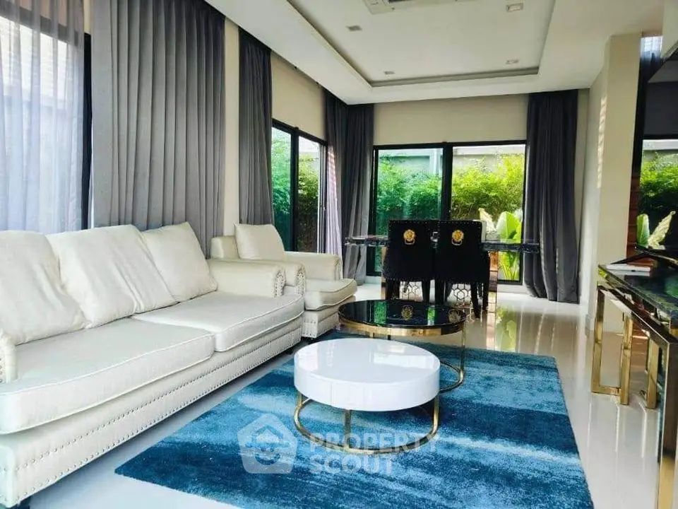 Luxurious modern living room with elegant furniture and large windows overlooking lush greenery.