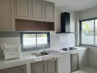 Modern kitchen with sleek cabinetry and gas stove, featuring large windows for natural light.