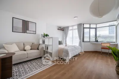Spacious modern bedroom with cozy seating area and large windows offering natural light.