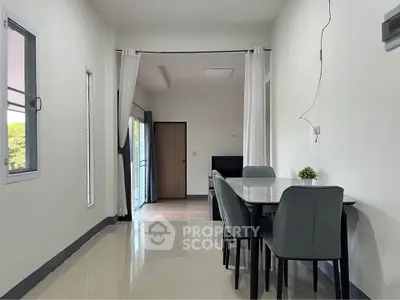 Modern dining area with sleek table and chairs, adjacent to a bright living room with natural light.