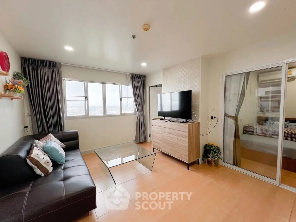Modern living room with large window and stylish decor, featuring a comfortable sofa and flat-screen TV.