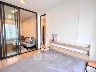 Modern bedroom with sliding glass doors leading to a cozy living area, showcasing contemporary design.
