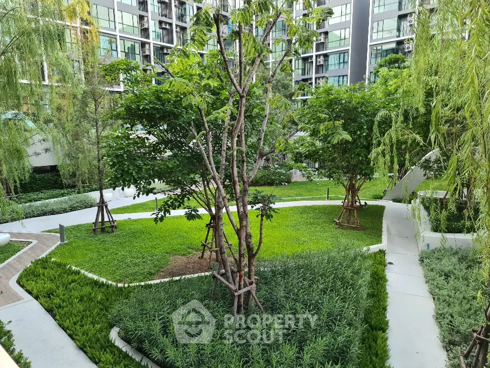 Lush green garden area in modern residential complex with well-maintained landscaping and trees.