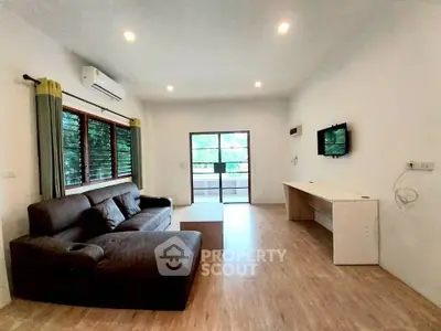 Spacious living room with modern sofa and large windows offering natural light.