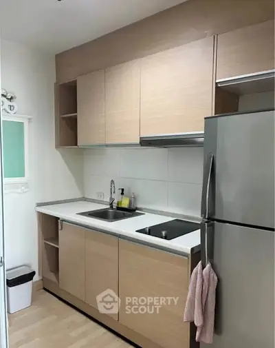 Modern kitchen with sleek cabinetry and stainless steel fridge in a compact layout.