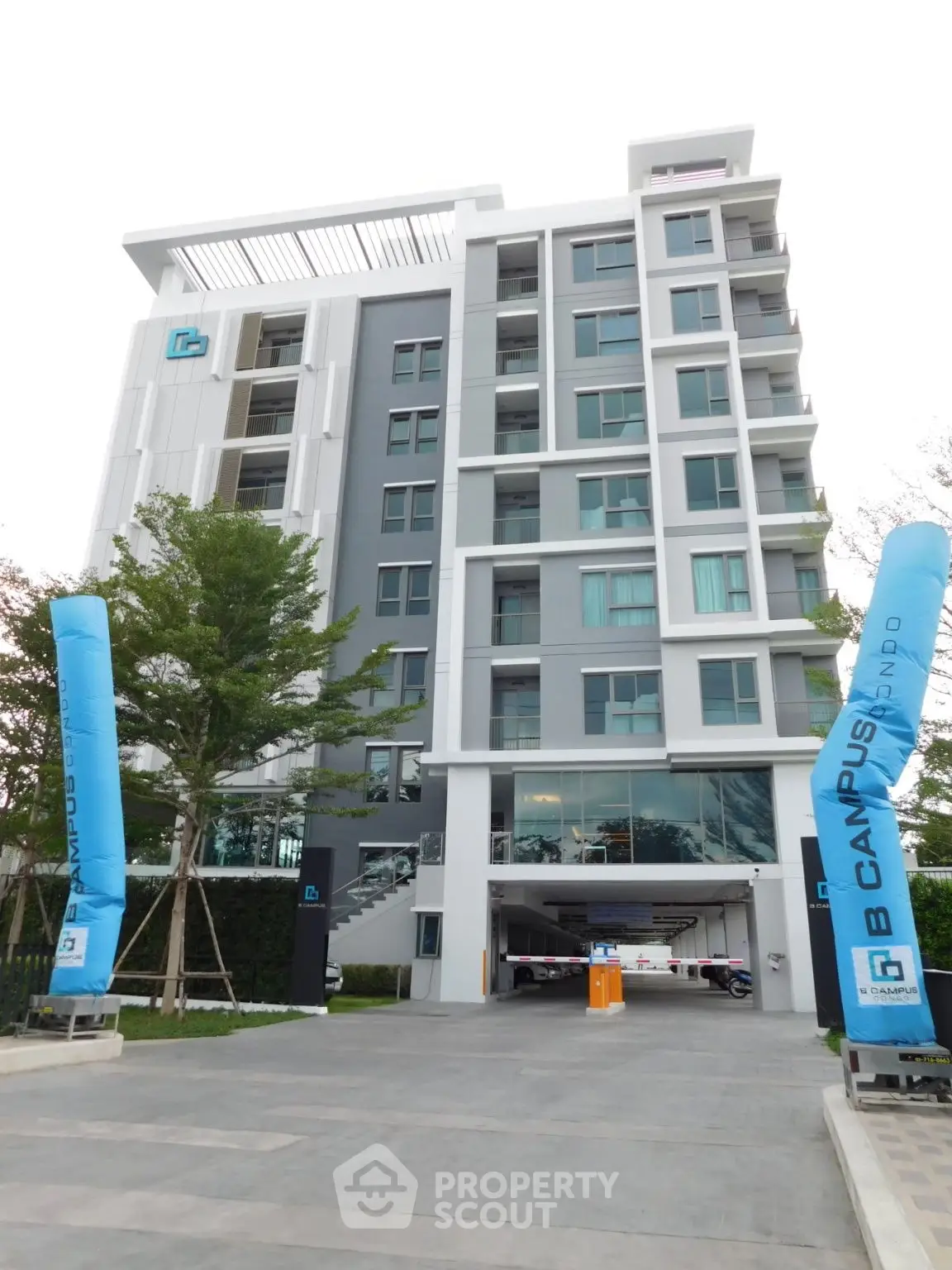 Modern multi-story apartment building with sleek design and ample parking space.