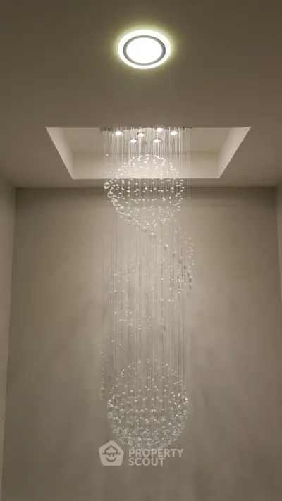 Elegant modern chandelier with crystal design in luxurious interior setting.