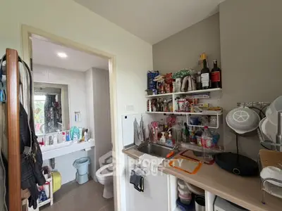 Compact kitchen with open shelving and adjacent bathroom in modern apartment