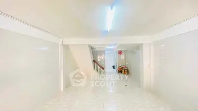 Spacious tiled interior with bright lighting and staircase, ideal for versatile use.