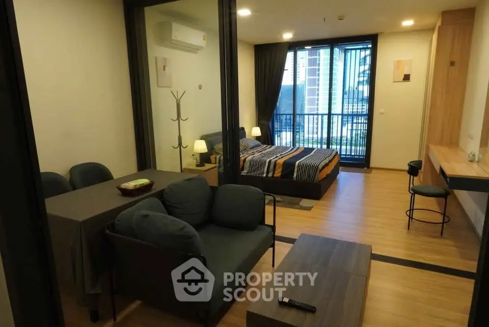 Modern studio apartment with open layout, featuring a cozy living area and bedroom with balcony access.