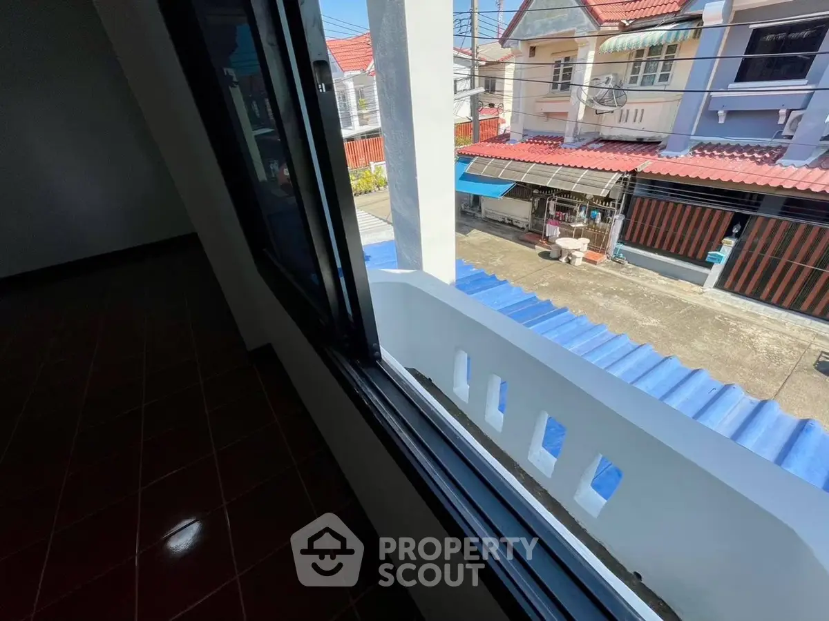 Charming neighborhood view from a second-story window with tiled roofs and street scene.