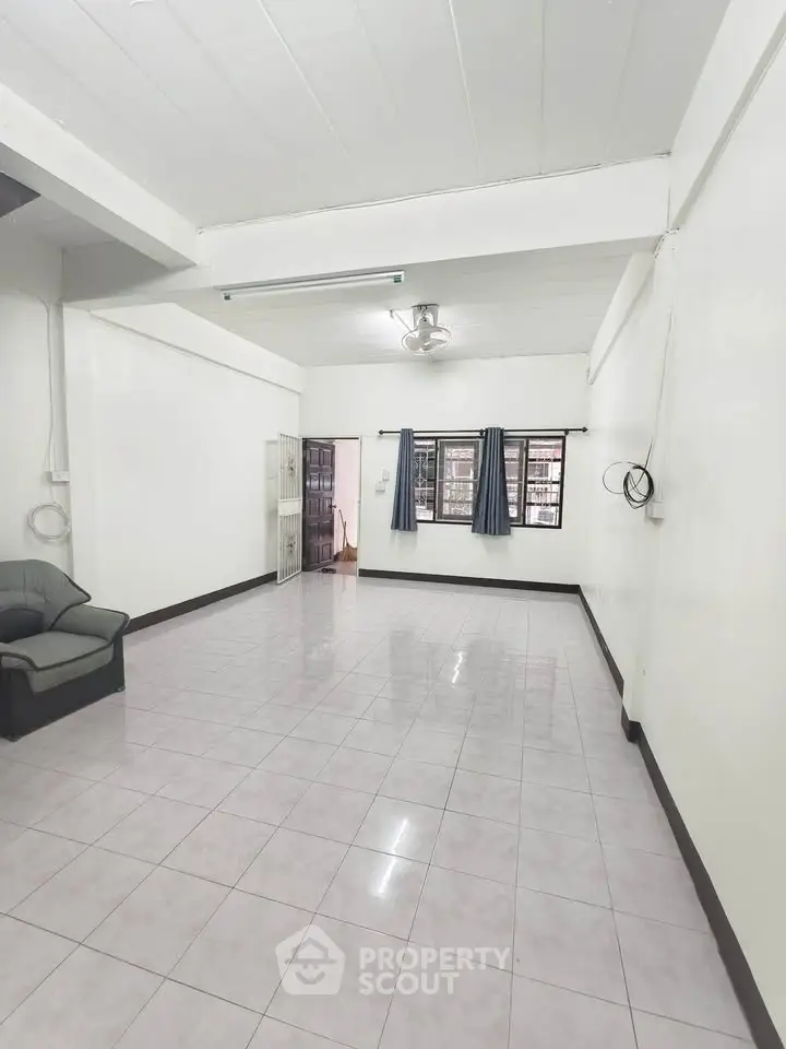 Spacious living room with tiled floor and large windows in a minimalist style.
