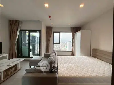 Modern studio apartment with large windows and balcony in urban setting.