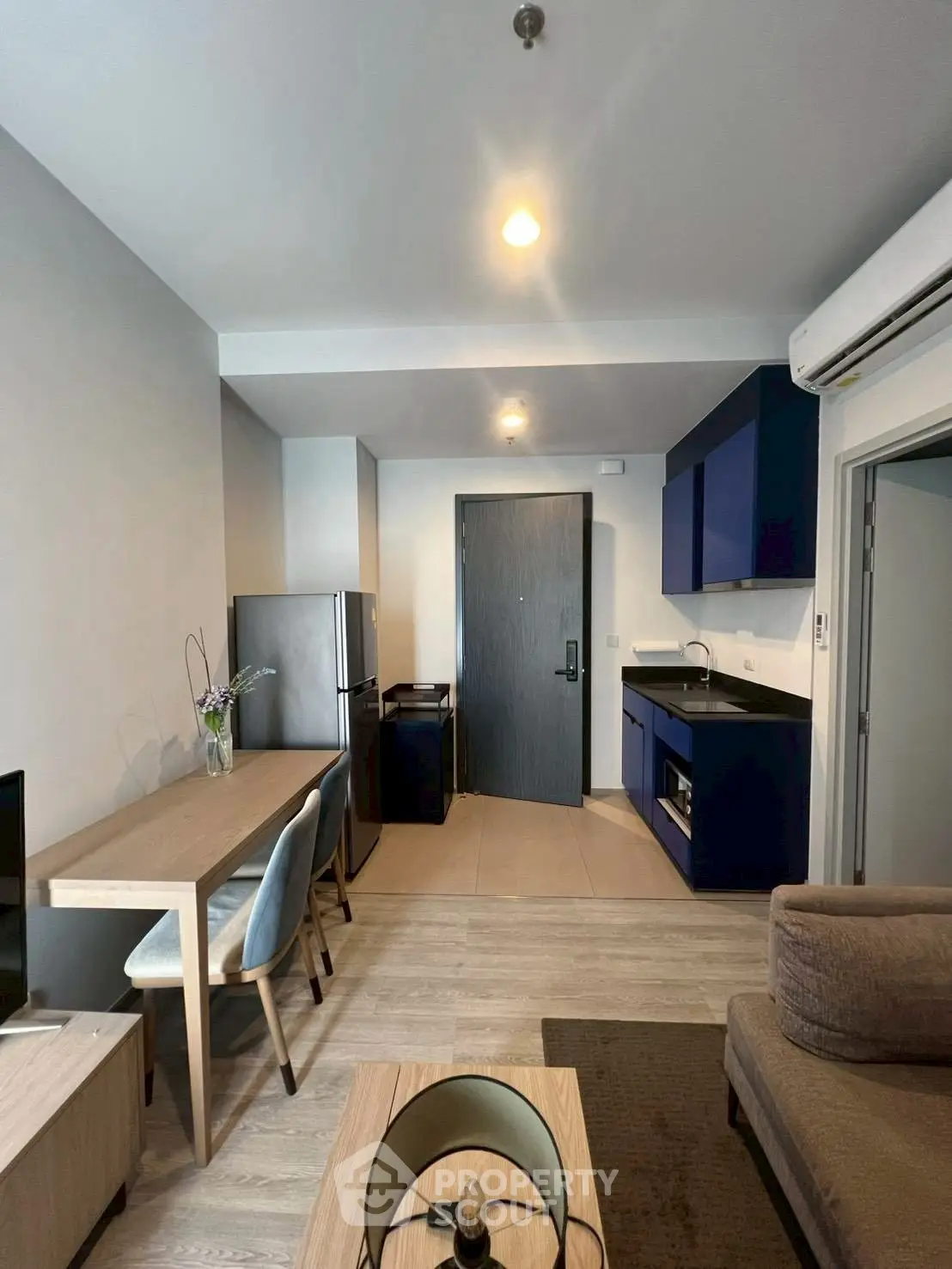 Modern open-plan living room with sleek kitchen and dining area, featuring stylish furniture and appliances.