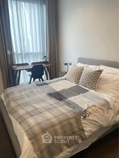 Cozy bedroom with modern decor and natural light, featuring a stylish desk and comfortable bed.