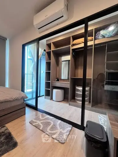 Modern bedroom with walk-in closet and balcony access, featuring sleek design and ample storage space.