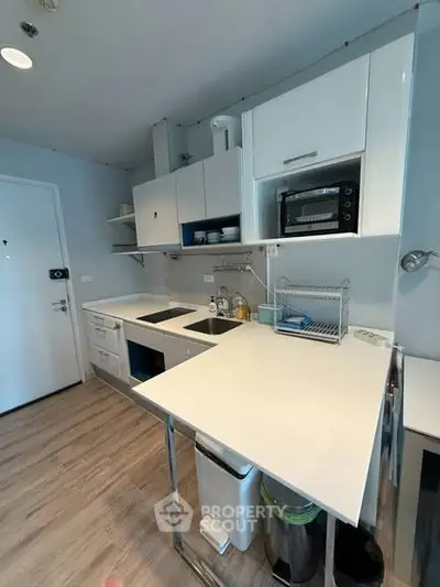 Modern compact kitchen with sleek white cabinets and built-in appliances