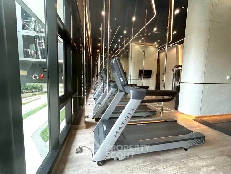 Modern gym with state-of-the-art treadmills and mirrored walls in luxury apartment complex.