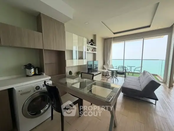 Modern open-layout living room with ocean view, featuring a washing machine and stylish furniture.