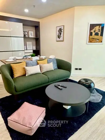 Modern living room with stylish green sofa, chic decor, and elegant coffee table in a cozy apartment setting.
