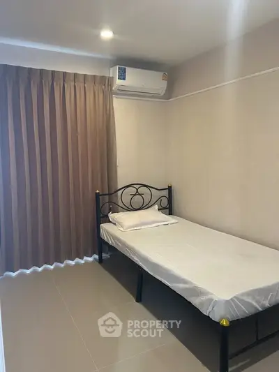 Cozy minimalist bedroom with single bed and air conditioning, ideal for comfortable living.