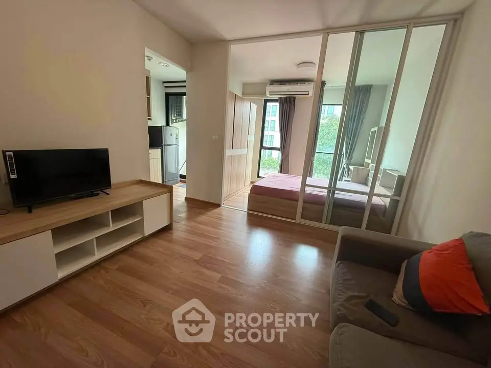 Modern apartment interior with cozy living room and bedroom, featuring wooden flooring and natural light.