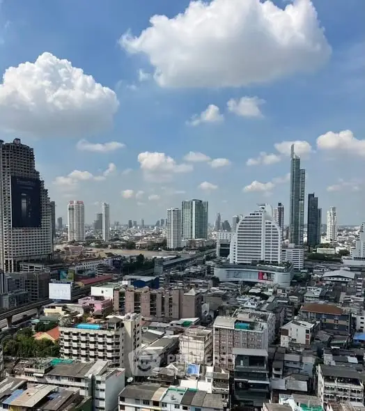 Stunning cityscape view showcasing modern skyscrapers under a clear blue sky with fluffy clouds.