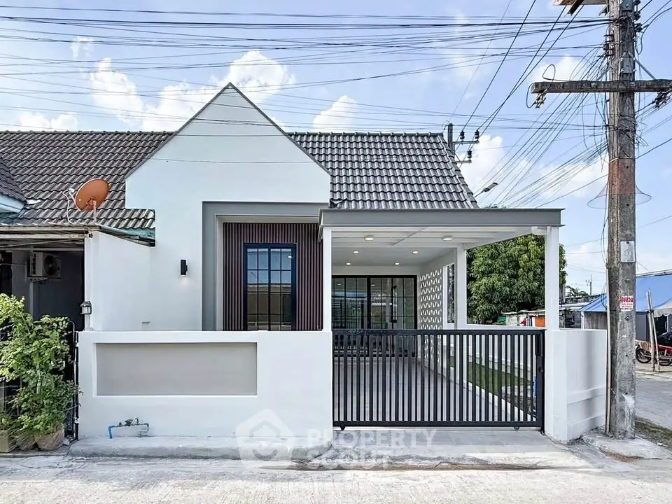 Charming single-story house with modern facade and gated driveway in a serene neighborhood.