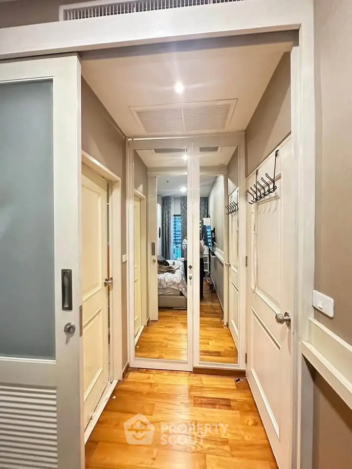 Stylish hallway with mirrored closet doors and wooden flooring in modern apartment.